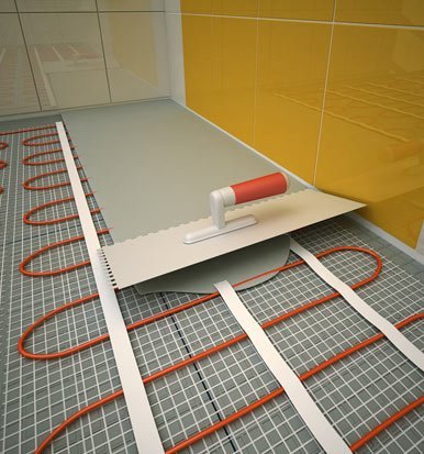 Pose d’un plancher chauffant hydraulique avec épandeur et câbles tubulaires rouges, sur chape et plots.