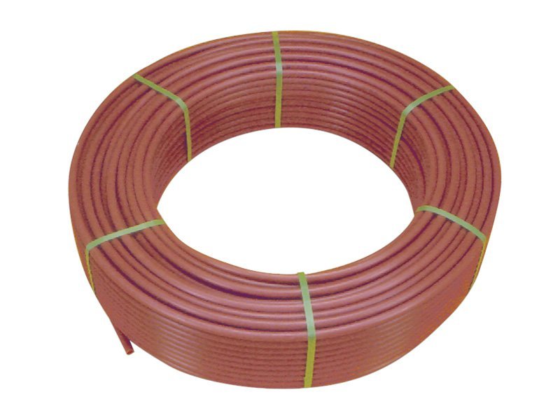 Rouleau de tube PER multicouche rouge, en bobine, prêt à être utilisé pour raccordements, posé en rond avec des liens élastiques jaunes. Per multicouche différence.